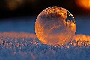 luces led 4 Close-up shot of a frozen bubble with warm reflections resting on a snowy surface at twilight.